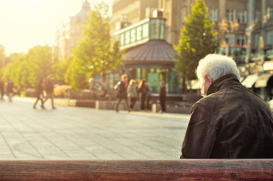 elderly man sitting on a bench in the city