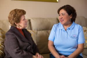 A home care giver talking to a client on a couch